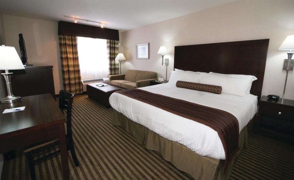een hotelkamer met een groot bed en een stoel bij Powell River Town Centre Hotel in Powell River