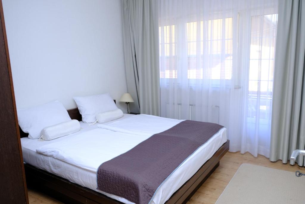 um quarto com uma cama com lençóis brancos e almofadas em Urban Apartment Visoko em Visoko
