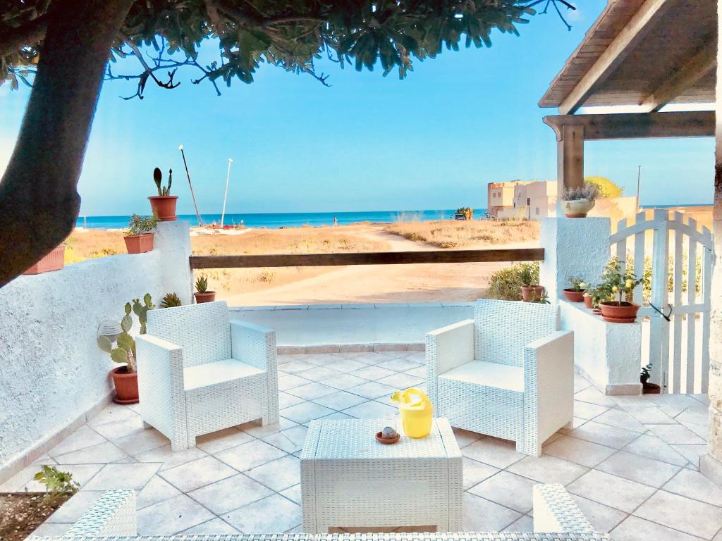 a patio with white chairs and a table and the ocean at Home Music & Love in Favignana