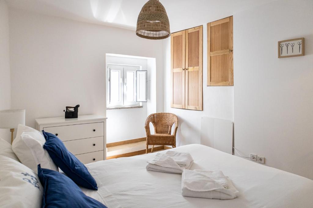 a bedroom with a white bed and a chair at Casa da Judiaria in Castelo de Vide