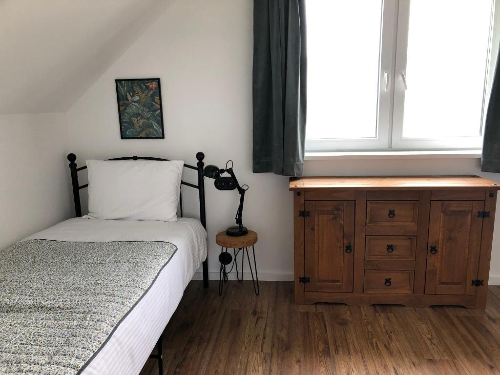 a bedroom with a bed and a dresser and a window at Goose Home and Garden in Łeba