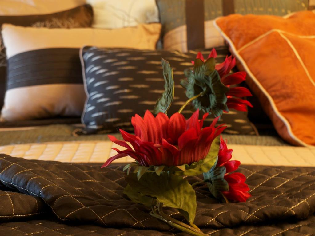 wazon z czerwonymi kwiatami na łóżku w obiekcie YPC Fitness & Accomodations w mieście Invermere