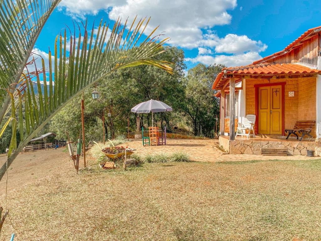 mały domek z żółtymi drzwiami i parasolką w obiekcie Serra a vista Chalé w mieście Prados
