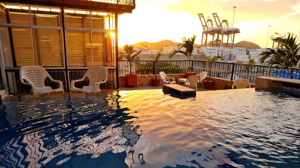 a swimming pool with white chairs and a building at Hotel Carolina Del Mar in Santa Marta