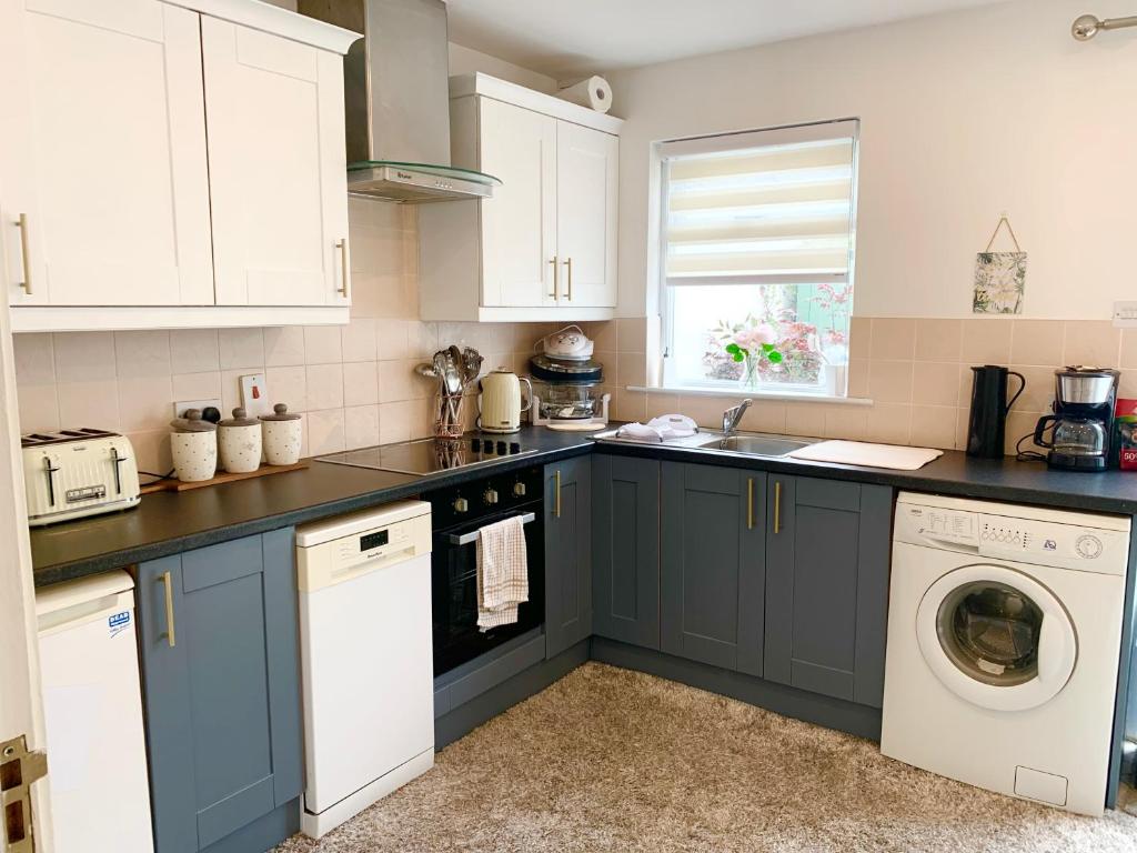 cocina con armarios azules, lavadora y secadora en Three-Bedroom Home in Tulfarris Village, Wicklow, en Blessington