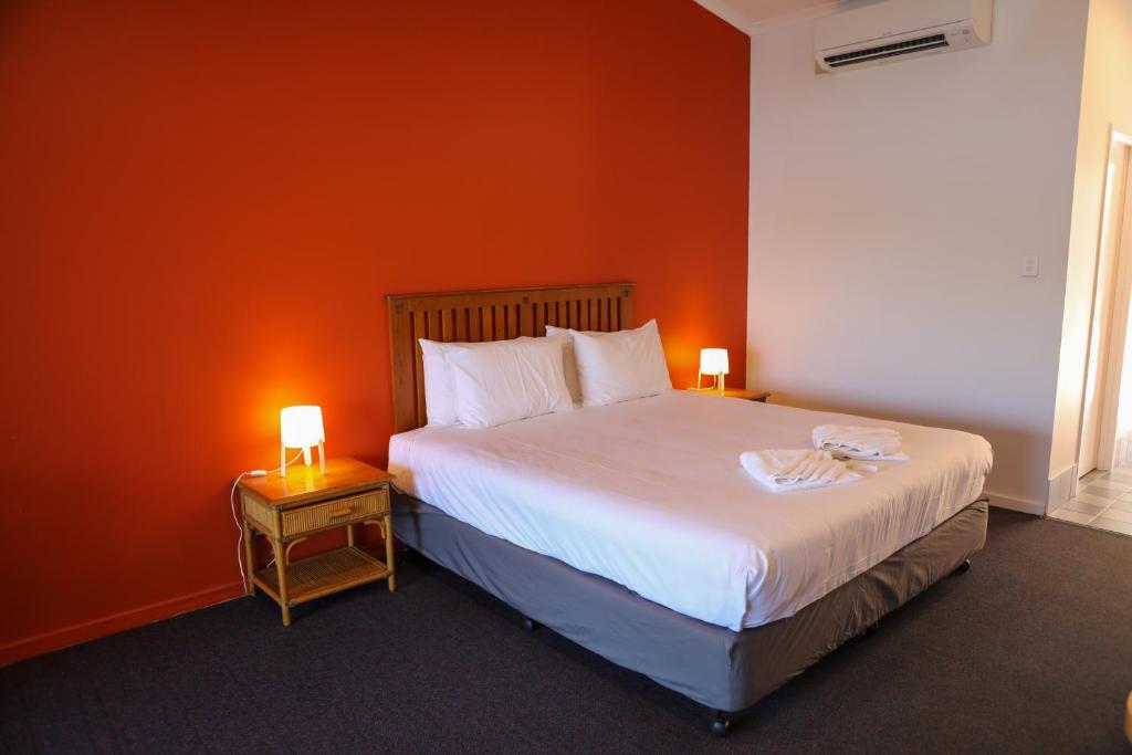 a bedroom with a large bed with an orange wall at De Lago Resort On Lake Bennett in Lake Bennett