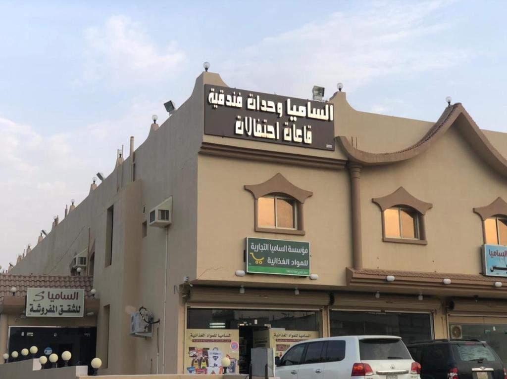 un bâtiment avec des voitures garées devant lui dans l'établissement Al Samia apartment, à Baljurashi