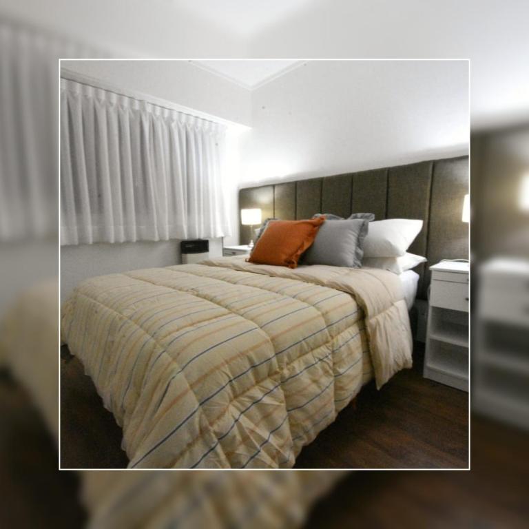 a bedroom with a large bed with a striped blanket at Depto.shanti-guemes Mar del Plata in Mar del Plata