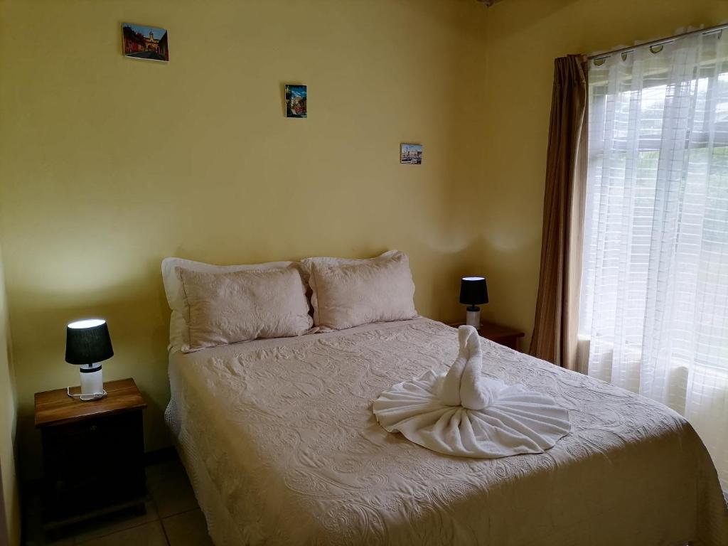 a bedroom with a bed with white sheets and a window at Cassidini House in Monteverde Costa Rica