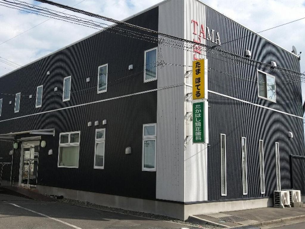 un edificio negro con un cartel en el costado en Tama Hotel en Ishinomaki