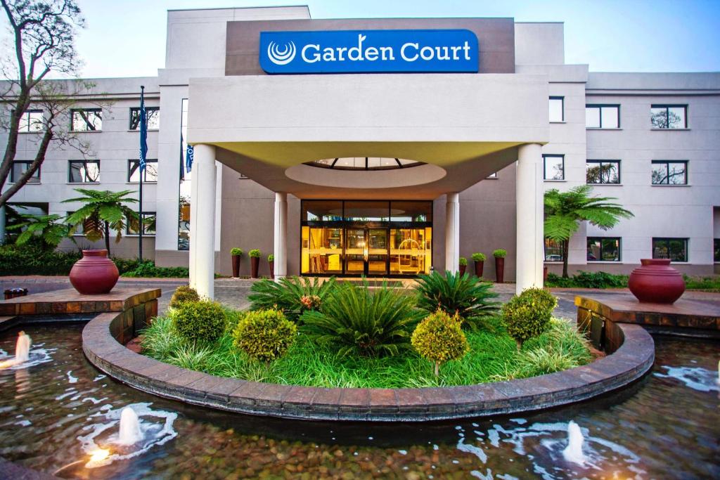 een tuinhofgebouw met een vijver ervoor bij Garden Court Hatfield in Pretoria