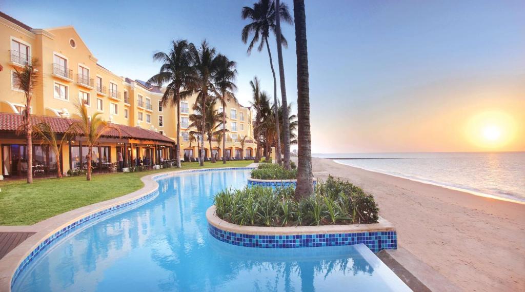 um resort com piscina junto à praia em Southern Sun Maputo em Maputo