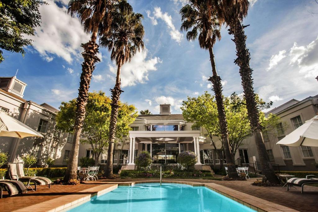 a pool in front of a house with palm trees at Garden Court Morningside Sandton in Johannesburg