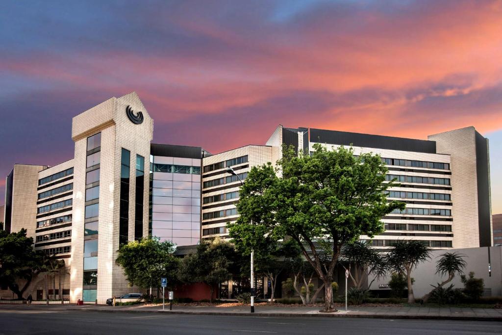 un grand bâtiment avec une horloge sur son côté dans l'établissement Southern Sun Pretoria, à Pretoria