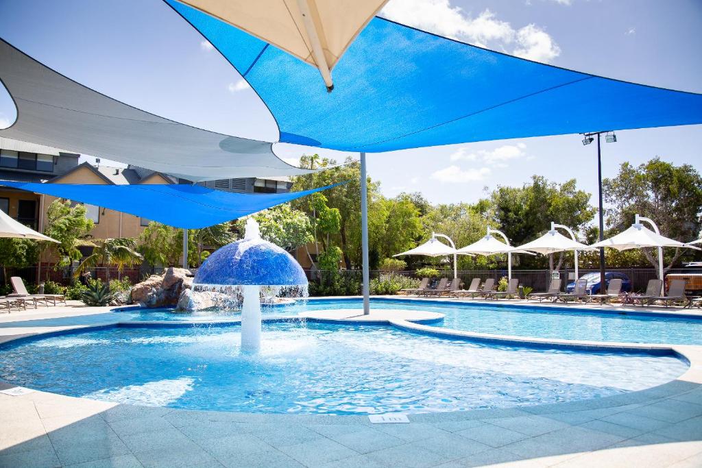 a pool with a blue umbrella and a fountain at Presidential Bungalow in Busselton