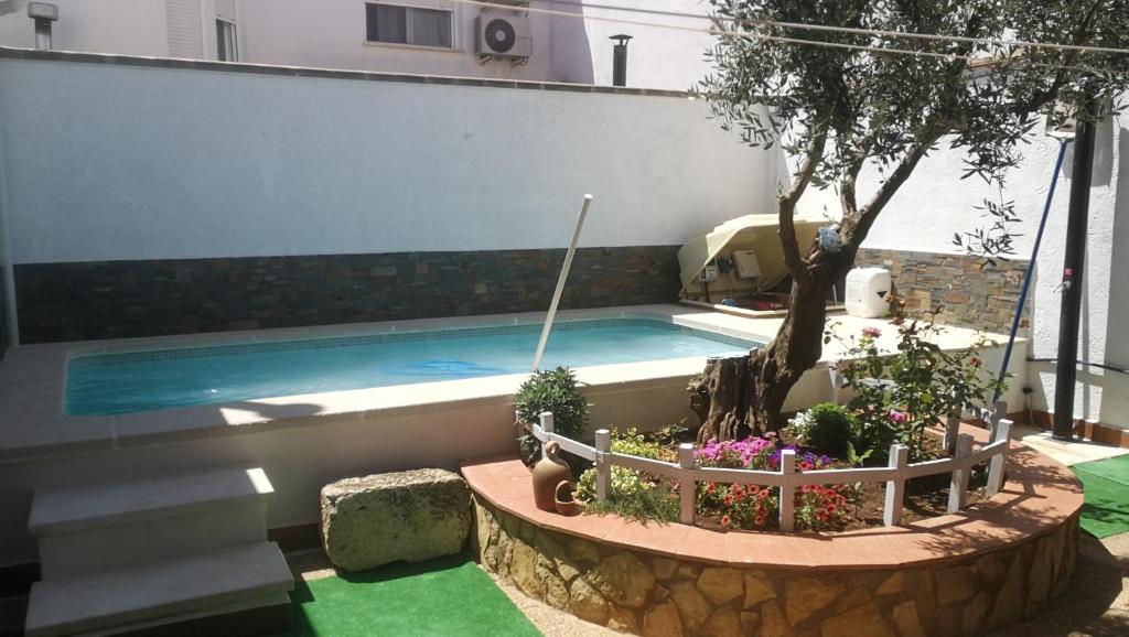 a swimming pool with a tree and some plants at CASA RURAL RIO CABRIEL in Villamalea