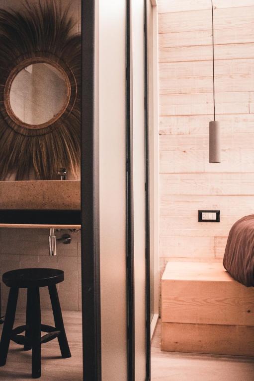 a room with a bed and a stool and a mirror at Laguna Suite B&B in Chioggia