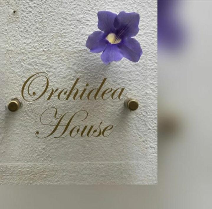 a sign with a purple flower on a white wall at Casa Orchidea in Taormina