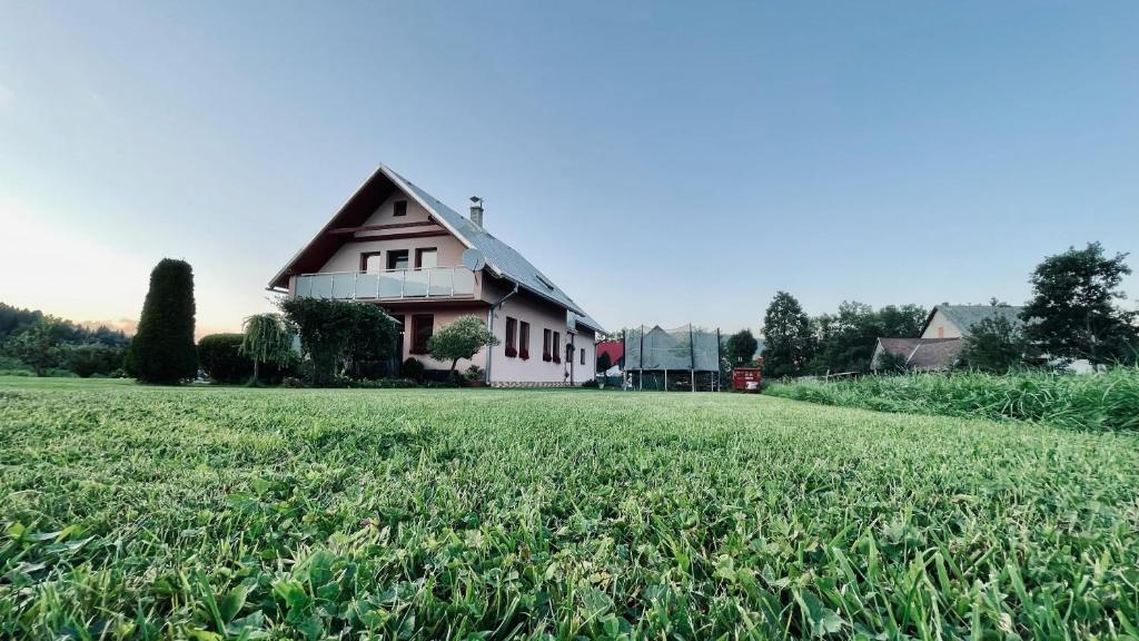 a house with a large grass field in front of it at Ubytovanie Taraj in Zuberec