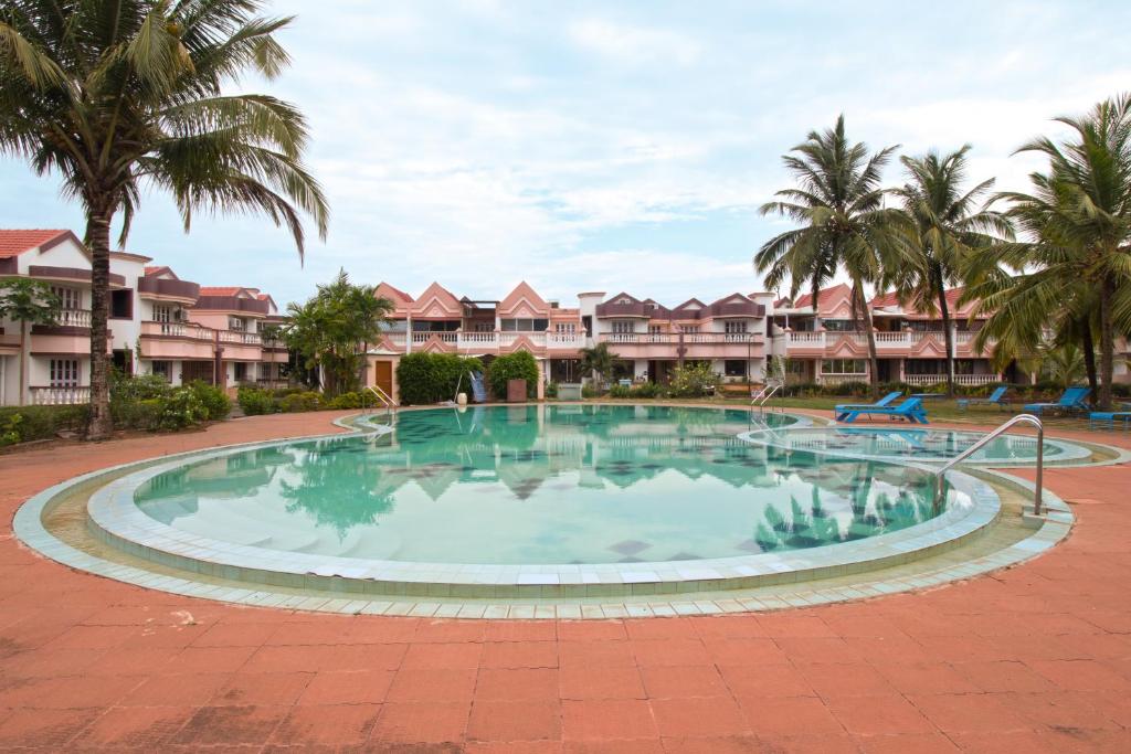 a large pool in the middle of a courtyard with palm trees at Lotus Eco Beach Resort - Goa in Benaulim