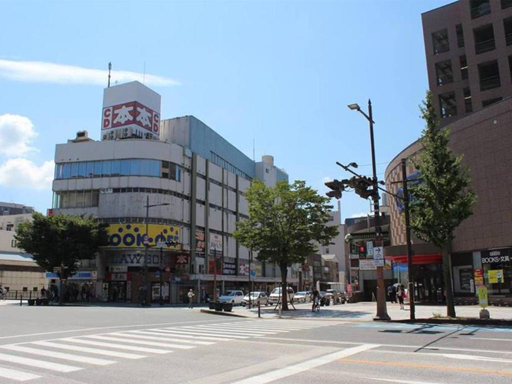 an empty city street with a building with a clock tower at Hostel TangaTable in Kitakyushu