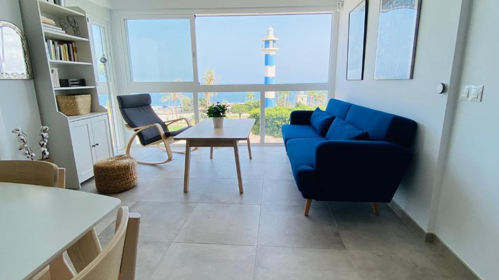 a living room with a blue couch and a table at El Faro de Torre del Mar in Torre del Mar