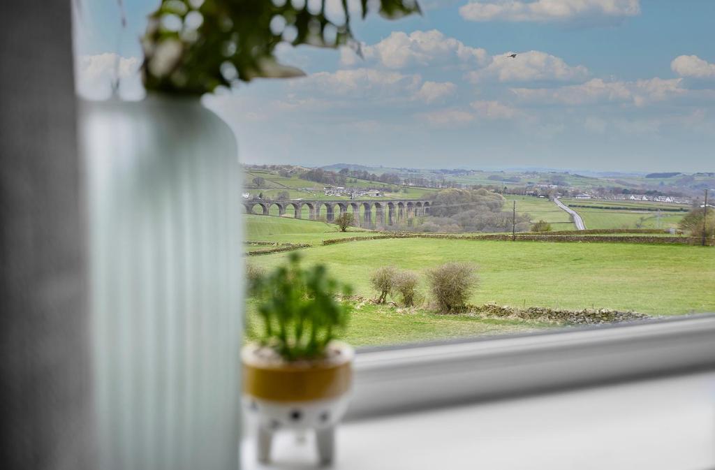 a white vase with a plant in a window at Haworth Home - Hot tub Cinema Games Room Sleeps 12 in Haworth