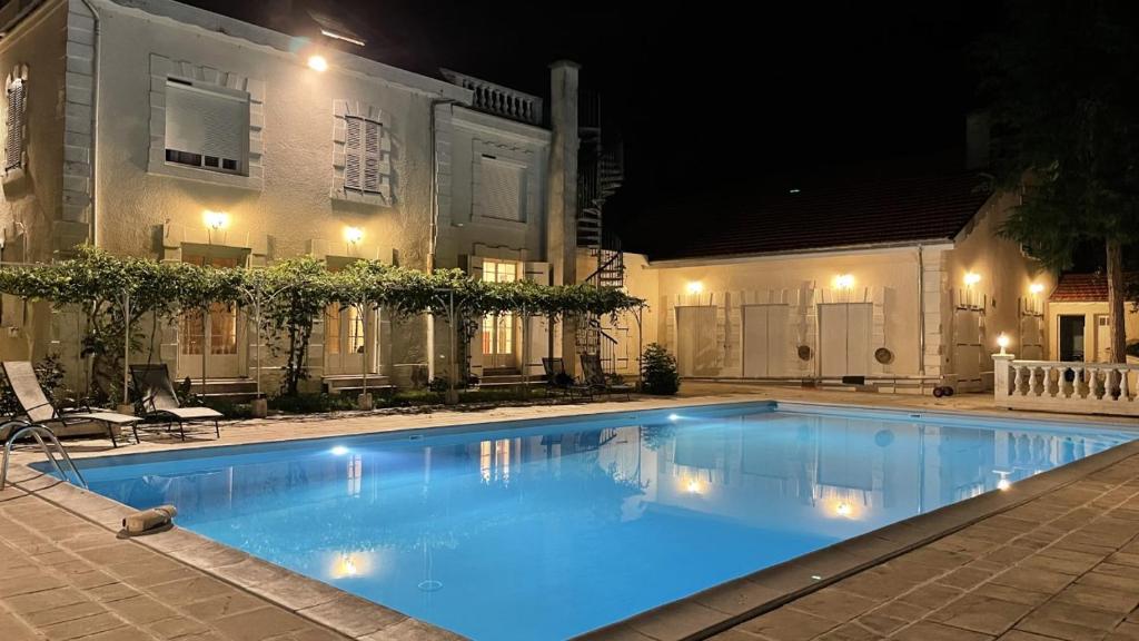 a swimming pool in front of a house at night at Logis Vélès in Aubin