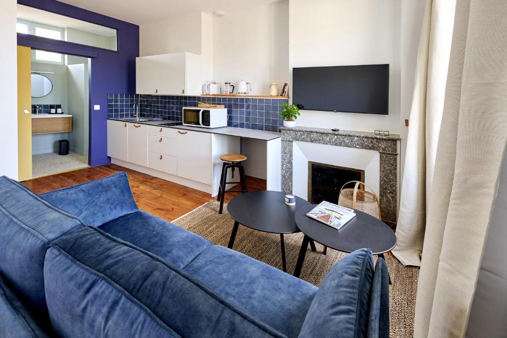 a living room with a blue couch and a fireplace at Le Nid - appartements Bordeaux Centre in Bordeaux