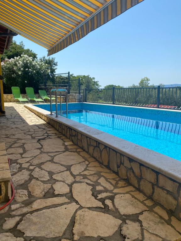 a large swimming pool with chairs and a fence at Villa Malnar in Vrh