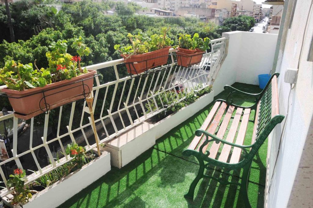 uma varanda com um banco e vasos de plantas em Pepoli Apartment up 4pax Parking em Trapani