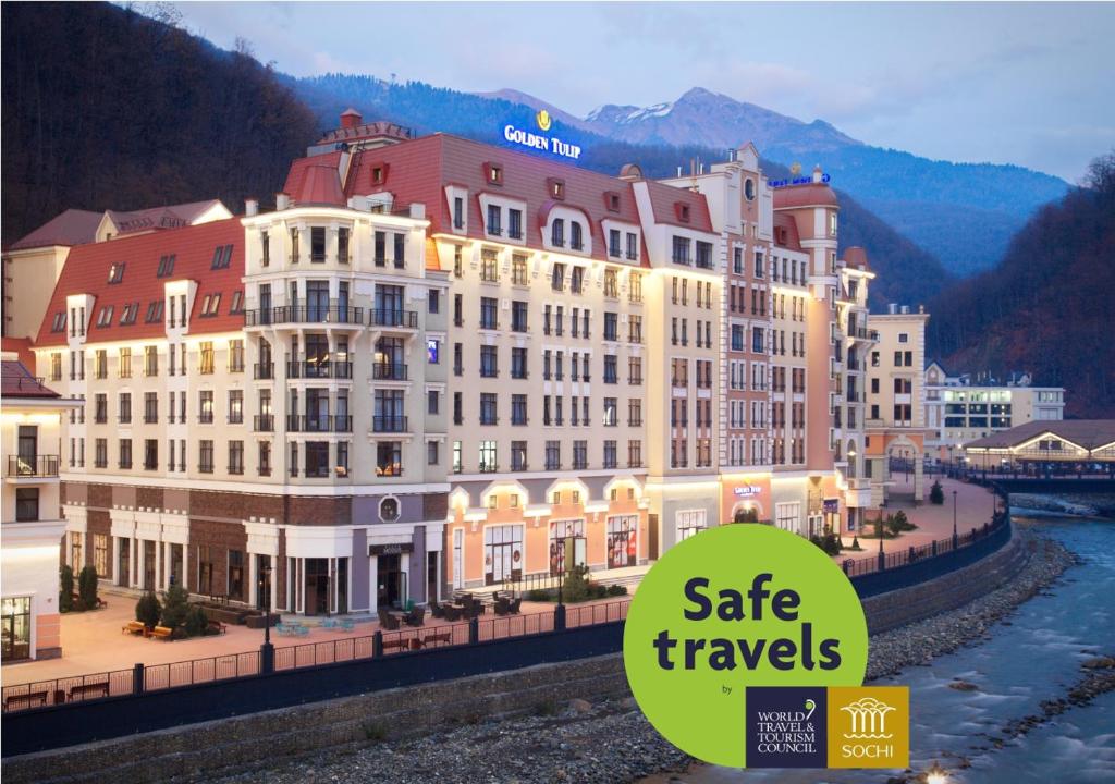 un rendimiento de un gran edificio junto a un río en Golden Tulip Rosa Khutor Hotel, en Estosadok