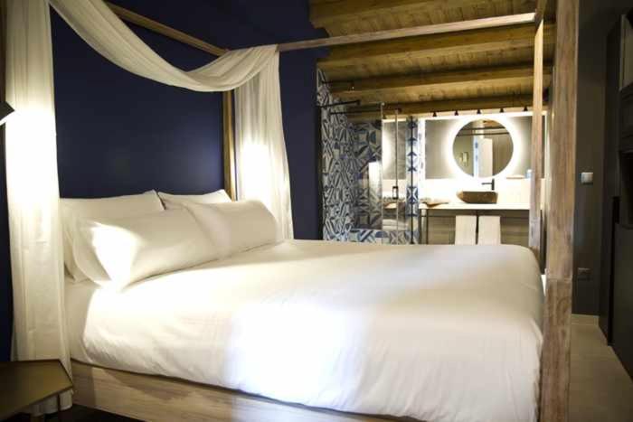 1 Schlafzimmer mit einem großen weißen Bett und einem Badezimmer in der Unterkunft Mochoruralhome matarraña suite in Beceite