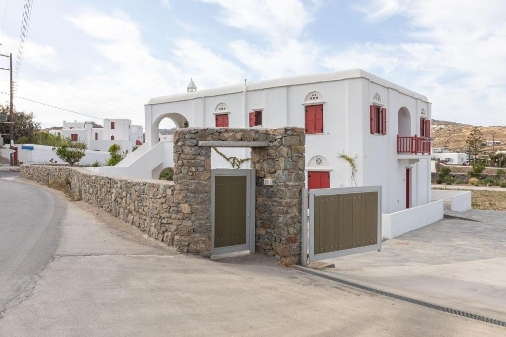 a white house with a stone wall and a gate at Marathi Mykonos in Klouvas