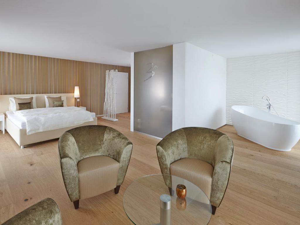 a bathroom with two chairs and a tub and a bed at Hotel AVA in Sempach Station