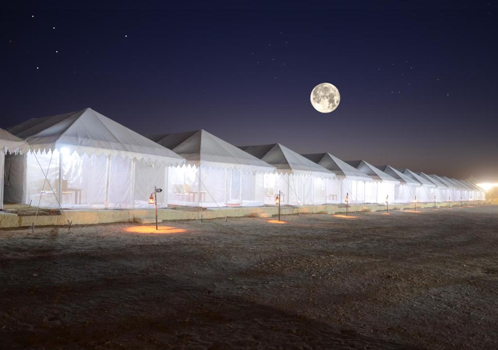 a row of white tents at night with the moon at Shiv Tara Desert Camp in Sām