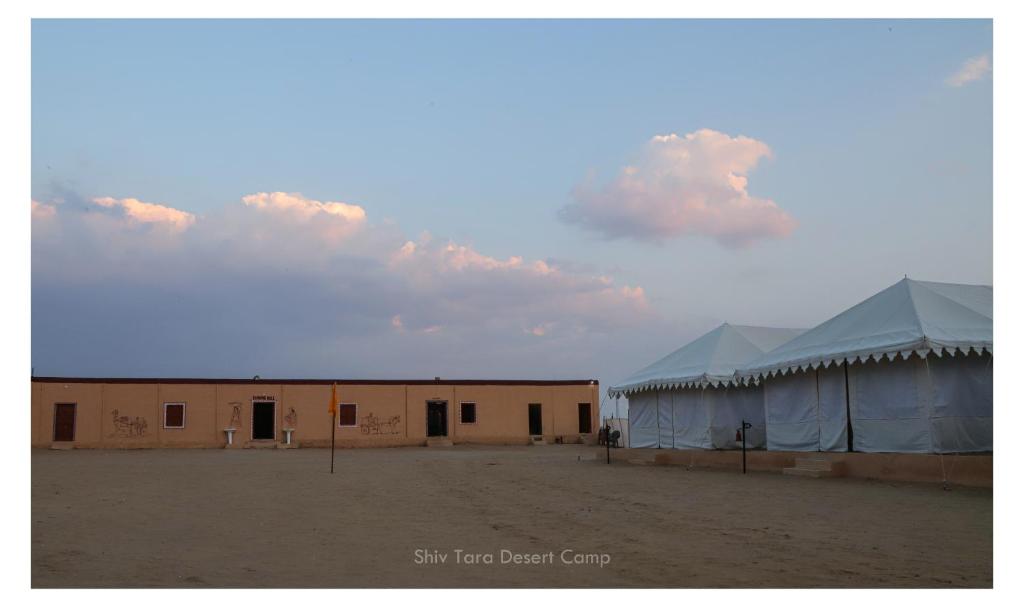 um edifício no meio de um deserto com duas tendas em Shiv Tara Desert Camp em Sām