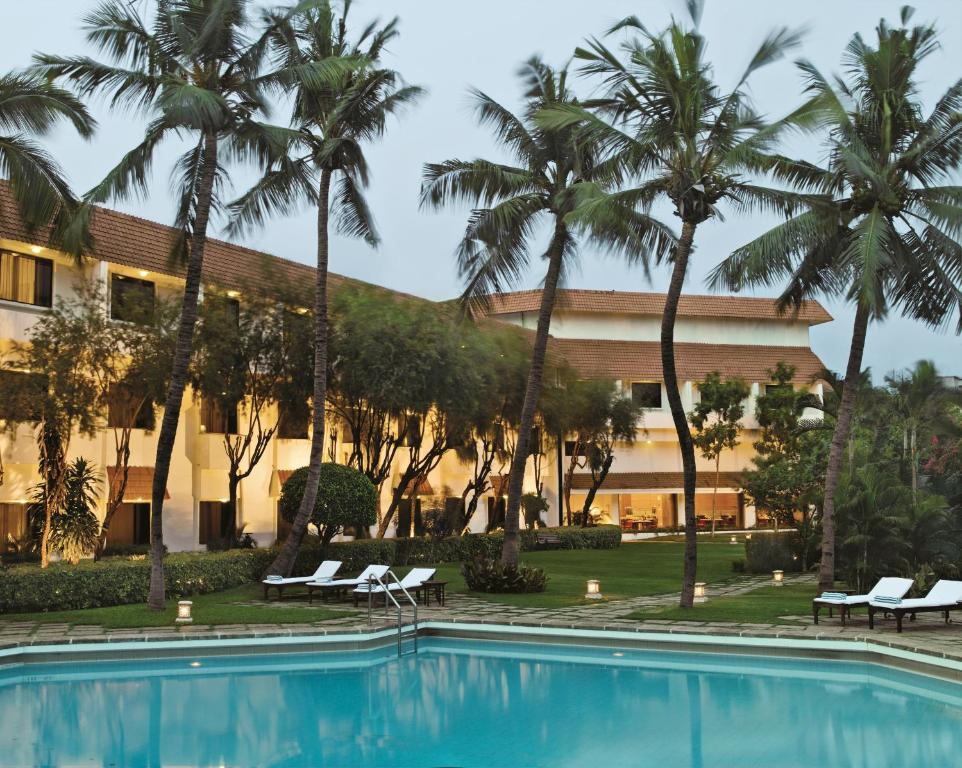 a resort with a swimming pool and palm trees at Trident Chennai in Chennai