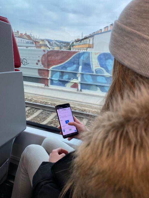 a woman sitting on a train while looking at a tablet at BeFree Hostel - Self-Service in Vienna