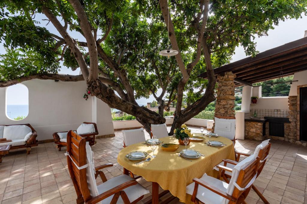 jadalnia ze stołem i krzesłami pod drzewem w obiekcie Villa Melinda - Charme Holidays w mieście Licata