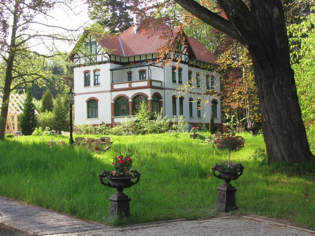 una casa grande con dos jarrones en el césped en Historische Pension Villa Uhlenhorst en Wernigerode