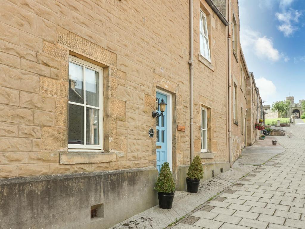 un bâtiment en briques avec une porte bleue dans une rue dans l'établissement Castlebrae, à Jedburgh
