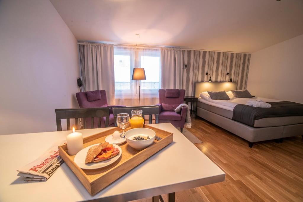 a living room with a bed and a table with a tray of food at Simloc Hotel Drottninggatan in Arjeplog