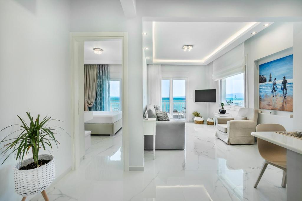 una sala de estar con muebles blancos y el océano en Beach Front Casa Elena, en Chaniotis