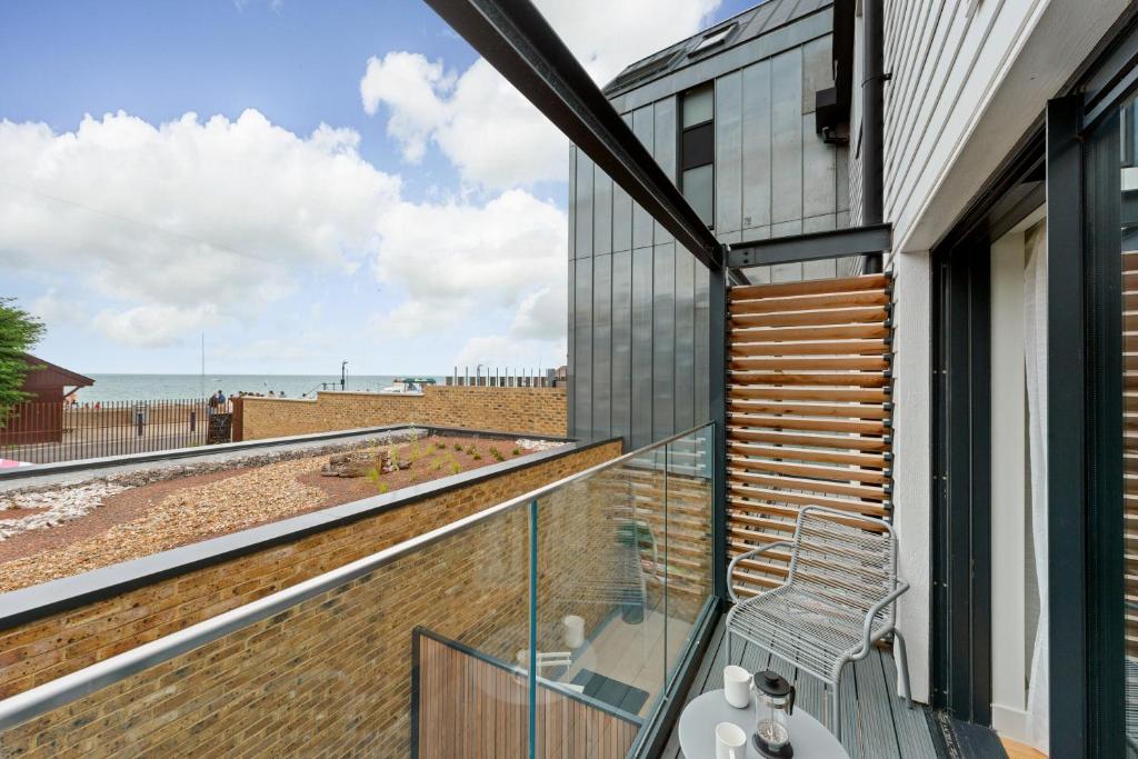 a balcony with a chair and a view of the beach at Home with sea views next to the beach! in Kent