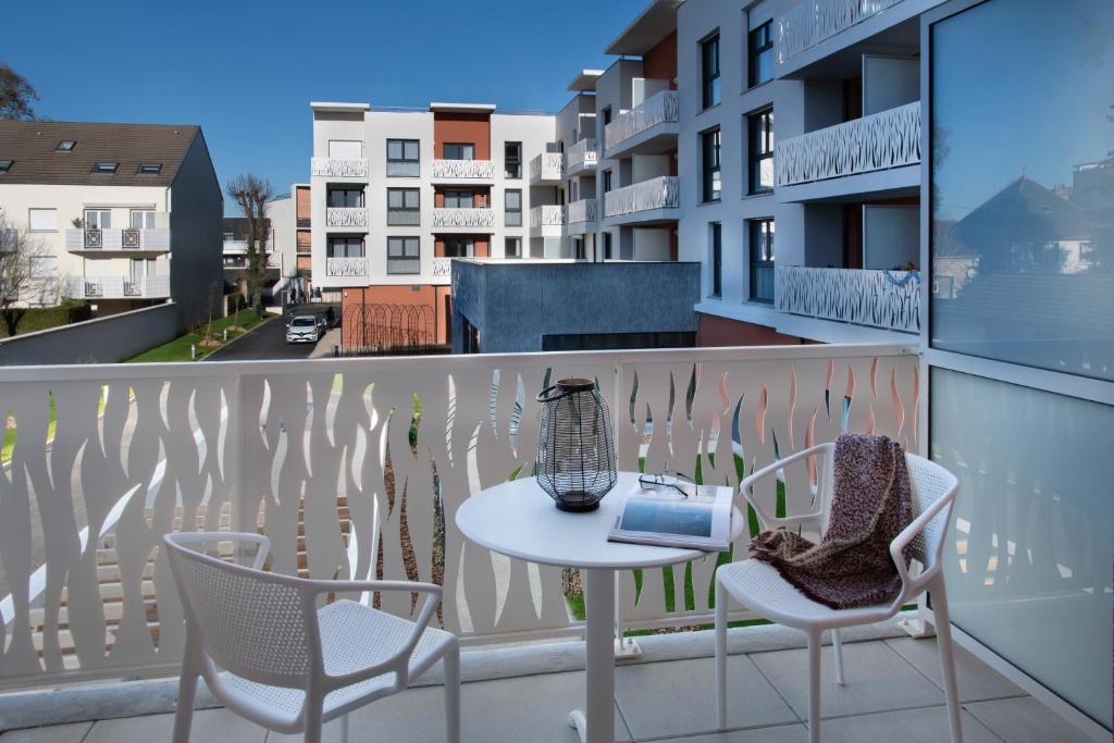 einen Balkon mit einem Tisch und Stühlen sowie einem Vogelkäfig darauf in der Unterkunft DOMITYS LES NOTES FLORALES in Combs-la-Ville