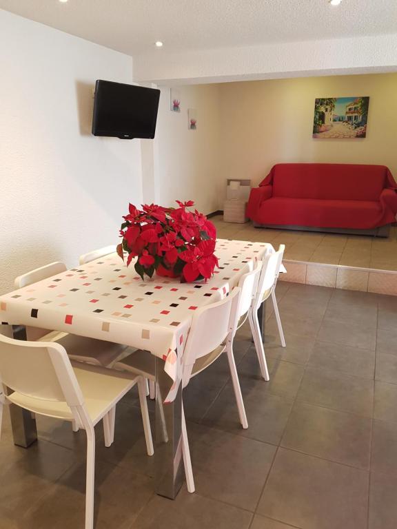 a table with red flowers on it with a red couch at Maison Saint Matteo in Lourdes