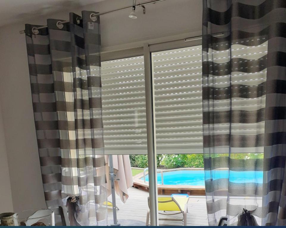ein Fenster mit einem Blinden in einem Zimmer mit einem Pool in der Unterkunft Villa de 2 chambres avec piscine privee jardin clos et wifi a Colonzelle in Colonzelle