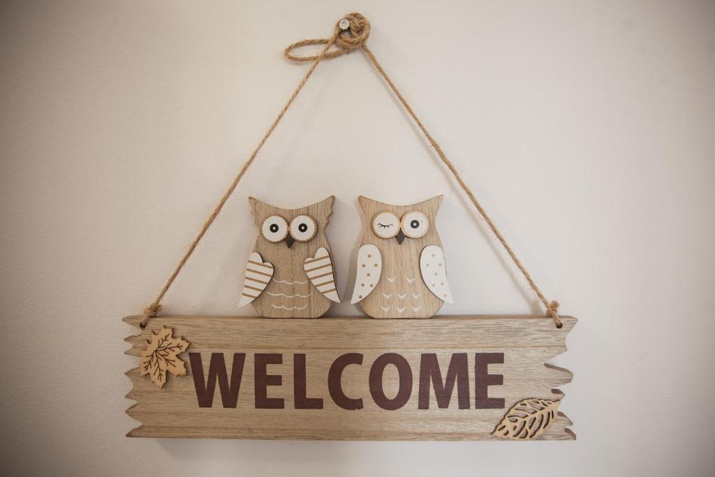 three owls sitting on a sign with a welcome sign at Rooms Klik in Postojna