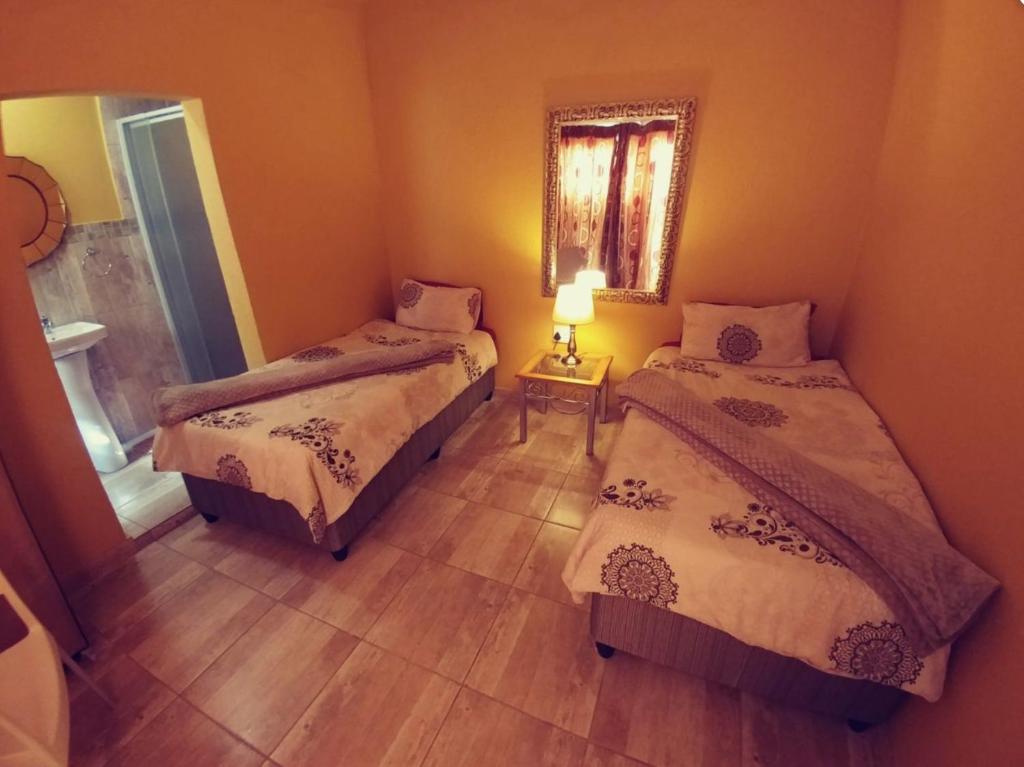 a bedroom with two beds and a mirror at The Loft Lynette's in Krugersdorp